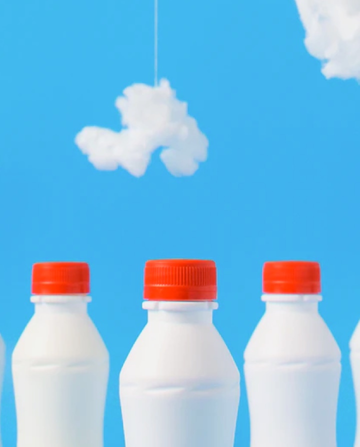 Three plastic milk bottles with a tuft of cloud in the background