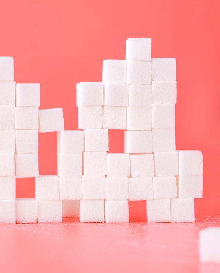 Stacked sugar cubes with a pink background