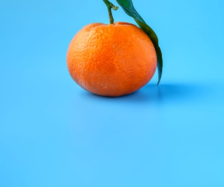 A tangerine on a light blue background